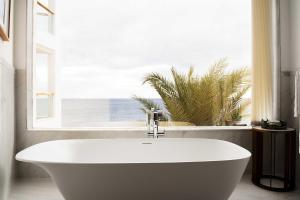 a white bath tub in a bathroom with a window at Hotel Fariones in Puerto del Carmen