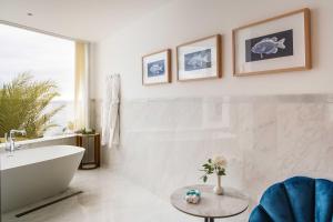 a white bathroom with a tub and a table at Hotel Fariones in Puerto del Carmen