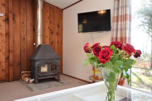 a vase of roses sitting on a table with a fireplace at Musselshell Lodge in Otter Ferry