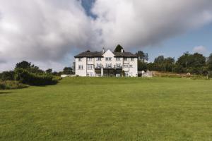 una gran casa blanca en la cima de un campo verde en Lyth Valley Country House, en Kendal