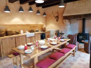 a kitchen with a wooden table with red cushioned chairs at Domaine du Ris de Feu Chambres d'hôtes de charme in Chalais