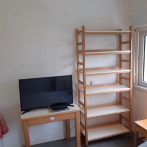 a room with a tv and a desk with a monitor and a shelf at BELLEVUE in Quétigny
