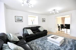 a living room with a black couch and a table at Large Stylish Cambridge House (4BR/Free Parking) in Cambridge
