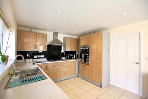 a large kitchen with wooden cabinets and a sink at Large Stylish Cambridge House (4BR/Free Parking) in Cambridge