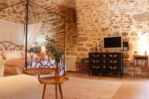 een slaapkamer met een bed en een tv aan een stenen muur bij Le Studio in Entraygues-sur-Truyère