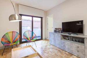 sala de estar con 2 sillas y TV de pantalla plana en Apartamento lujo castellana chamartín, en Madrid