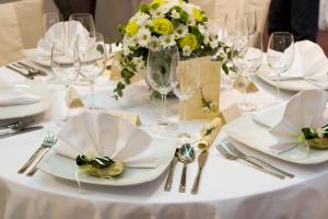 een witte tafel met borden en glazen en een vaas met bloemen bij Hotel Dania in Silkeborg