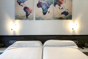 two beds in a bedroom with paintings on the wall at Pensión Donostiarra in San Sebastián