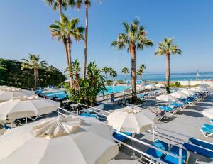 una fila de sombrillas blancas, palmeras y el océano en Monica Isabel Beach Club en Albufeira