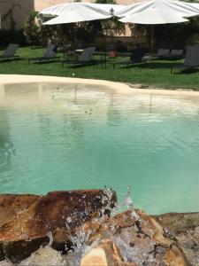 a pool of blue water with two white umbrellas at Hotel Samka in Salta