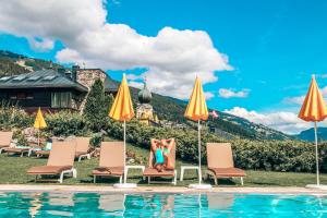 a woman sitting in a chair next to a swimming pool at Hotel Saalbacher Hof in Saalbach-Hinterglemm