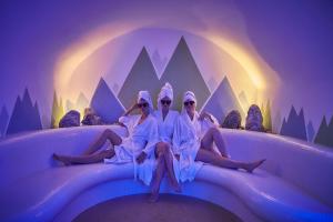 a group of three women sitting on a bed with the moon at Hotel Saalbacher Hof in Saalbach-Hinterglemm