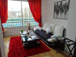uma sala de estar com um sofá e um tapete vermelho em La bambouseraie em Montrouge