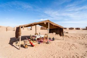 a tent with a table and chairs in the desert at Berber Camp & Desert Tours in Mhamid