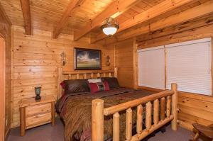 um quarto com uma cama num chalé de madeira em Smokey Max Cabin em Pigeon Forge