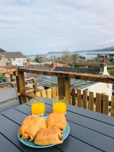 a table with a plate of bread and two glasses of orange juice at Artro House in Pembrokeshire