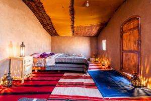 a bedroom with a bed and a large rug at Berber Camp & Desert Tours in Mhamid