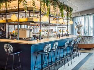 eine Bar in einem Restaurant mit blauen Barhockern in der Unterkunft Fletcher Hotel-Restaurant Scheveningen in Scheveningen
