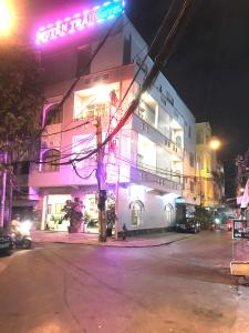 ein Gebäude an einer Straße in der Nacht mit lila Lichtern in der Unterkunft Huyen Tran Hotel in Cần Thơ