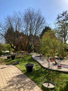 un parque con bancos, árboles y un camino en Le Chai De La Rose SPA et Séances Bien être en Doué-la-Fontaine