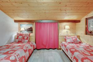 2 Betten in einem Zimmer mit roten Vorhängen in der Unterkunft Atray C3 in Morzine