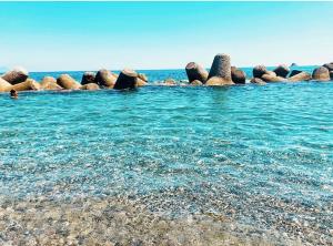 eine Gruppe von Felsen im Wasser an einem Strand in der Unterkunft La Risacca Suite in Patti