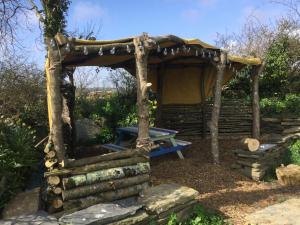 a wooden shelter with a picnic table in a garden at Horsemans Stargazing Tent in Kingsbridge
