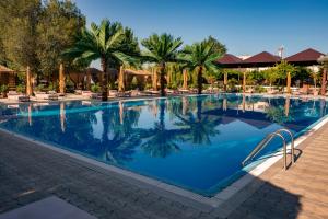 una piscina en un complejo con palmeras y sillas en Cross Health Spa Center, en Ereván