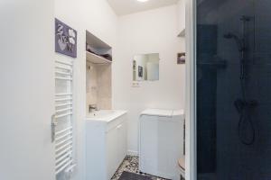 a white bathroom with a shower and a sink at Les Claviers in Vitré