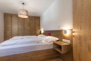 Schlafzimmer mit einem großen Bett mit einem Kopfteil aus Holz in der Unterkunft HAUS GREG in Toblach