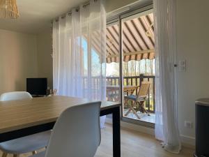 a dining room with a table and chairs and a balcony at Hyper Centre - 2 PIÈCES tout confort - Terrasse - ascenseur - in Cabourg