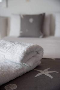 a white towel on a bed with a starfish on the floor at Fisilanis Beachfront Hotel in Logaras