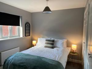a bedroom with a bed with a blue blanket and two lamps at Silver Stag Properties, Spacious 3 BR Haven in Ashby de la Zouch
