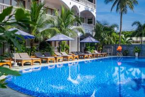 Brenta Phu Quoc Hotel في فو كووك: مسبح وكراسي ومظلات بجانب مبنى