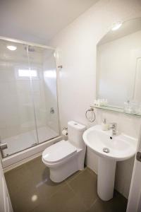 a white bathroom with a toilet and a sink at Hostal Ventisqueros in Punta Arenas