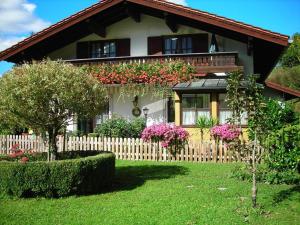 une maison avec une clôture et des fleurs devant elle dans l'établissement Ferienwohnung Rutz, à Ruhpolding