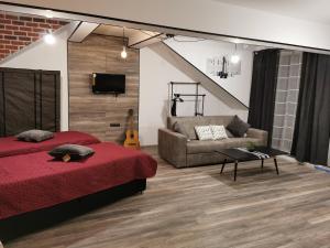 a bedroom with a red bed and a couch at Urban Music Studio byPMM in Plovdiv