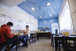 two men sitting at tables in a restaurant with a blue ceiling at Hostal Ventisqueros in Punta Arenas