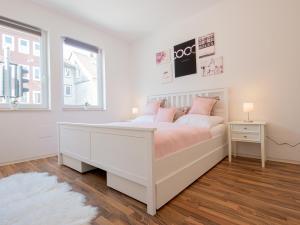 a white bedroom with a white bed with pink pillows at EUPHORAS - Top ausgestattete Ferienwohnung mit 105 qm und 3 Schlafzimmern in Clausthal-Zellerfeld +1 photo