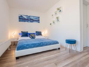 um quarto branco com uma cama azul e um banco azul em EUPHORAS - Top ausgestattete Ferienwohnung mit 105 qm und 3 Schlafzimmern em Clausthal-Zellerfeld