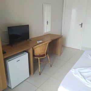 a desk with a television and a chair in a room at Tropical Praia Hotel in Aracaju