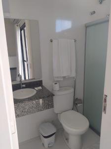 a white bathroom with a toilet and a sink at Tropical Praia Hotel in Aracaju