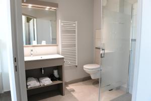 La salle de bains est pourvue d'un lavabo, de toilettes et d'une douche. dans l'établissement Hotel Les Galets Bleus, à Cayeux-sur-Mer