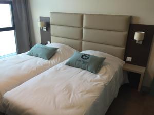 two beds in a hotel room with two pillows on them at Hotel Les Galets Bleus in Cayeux-sur-Mer