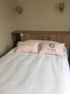 a white bed with two pink pillows on it at Hotel Les Galets Bleus in Cayeux-sur-Mer