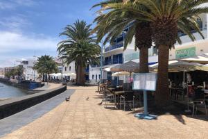 un complejo con mesas, sillas y palmeras en The Penthouse Ascona in El Charco, en Arrecife
