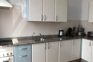Una cocina con gabinetes blancos y un fregadero. en The Penthouse Ascona in El Charco, en Arrecife 10 fotos más