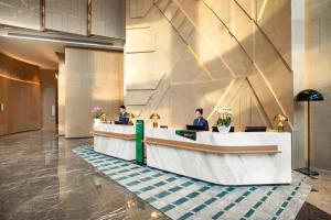 two people sitting at a reception desk in a lobby at Holiday Inn Shanghai Nanjing Road by IHG in Shanghai