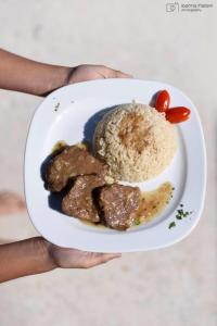 a person holding a plate of food with meat and rice at Fisilanis Beachfront Hotel in Logaras