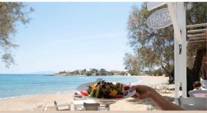 a person holding a plate of food on the beach at Fisilanis Beachfront Hotel in Logaras